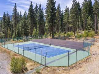 Enjoy outdoor recreation with this private tennis court, nestled amidst a serene forest setting.
