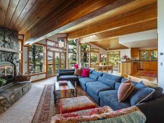 Experience breathtaking mountain views from this stunning living room, featuring a grand stone fireplace and expansive windows that flood the space with natural light.