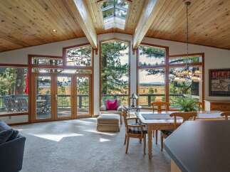 Experience breathtaking panoramic views from this stunning living space, featuring expansive windows and a unique skylight that flood the room with natural light.