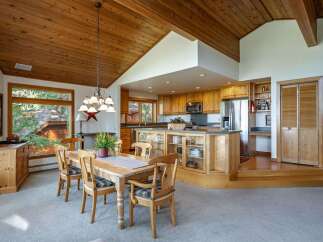 Experience the warmth of this inviting dining and kitchen area, featuring a vaulted wood-paneled ceiling and a charming chandelier.