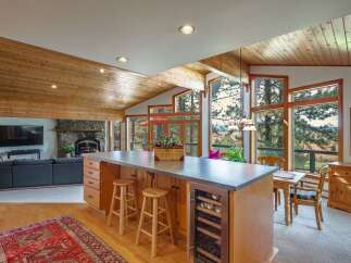 Experience breathtaking panoramic views from this stunning open-concept living space, featuring a vaulted wood-paneled ceiling and expansive windows.