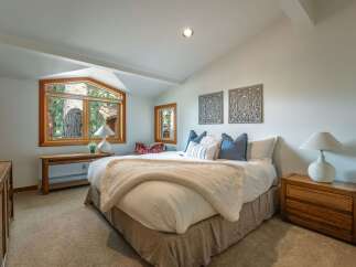 Experience serene mountain living in this charming bedroom, featuring a large bay window with picturesque forest views.