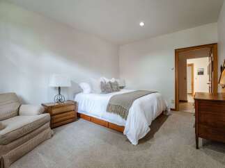 This cozy bedroom features a comfortable queen-size bed with crisp white linens and a plush throw blanket, perfect for relaxation.