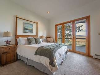 Experience serene living in this charming bedroom, featuring a cozy four-poster bed adorned with a plush knit throw and decorative pillows.
