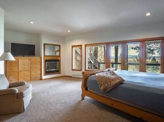 Experience breathtaking mountain views from this stunning bedroom, featuring a cozy fireplace and a large television for ultimate relaxation.