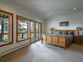 Experience breathtaking views from this master bedroom, featuring expansive windows that frame the natural landscape.