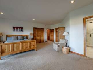 This spacious master bedroom features a beautiful wooden bed frame complemented by two matching nightstands and lamps.