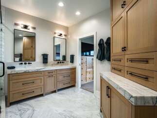 Experience luxury in this modern bathroom featuring a spacious double vanity with sleek wooden cabinetry and elegant marble countertops.