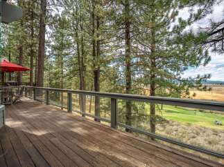 Enjoy breathtaking views from this expansive deck, perfect for outdoor entertaining or simply relaxing amidst the tall pine trees.