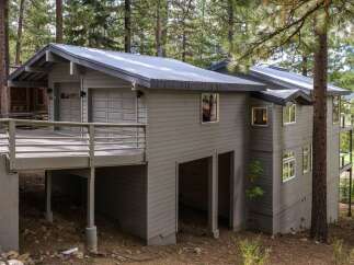 Nestled among tall pine trees, this modern home offers a unique architectural design with a metal roof and siding.