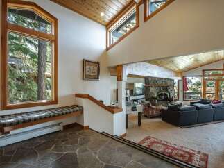 Experience the ultimate mountain retreat in this stunning living room, featuring a grand stone fireplace and soaring vaulted ceilings with exposed wood beams.