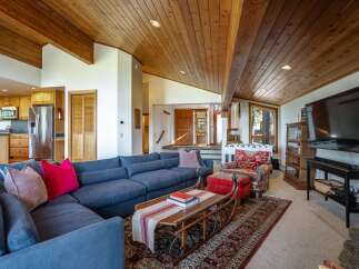 Experience rustic charm in this spacious living area, featuring a large sectional sofa perfect for gatherings and a unique sled-shaped coffee table that adds a touch of whimsy.