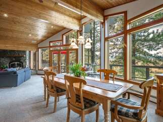 Experience breathtaking mountain views from this stunning dining area, featuring a rustic wooden table and chairs perfect for family gatherings.