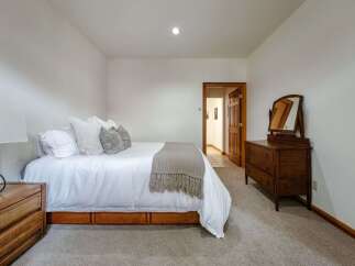 This inviting bedroom features a comfortable queen-size bed adorned with crisp white linens and plush decorative pillows.