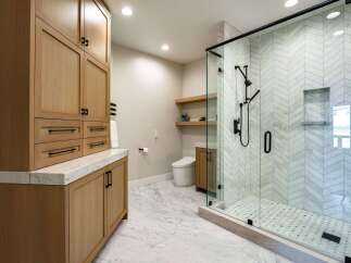 Experience modern luxury in this stunning bathroom featuring a spacious walk-in shower with elegant herringbone tilework and a sleek glass enclosure.