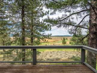 Enjoy breathtaking views from this property's deck, overlooking a scenic golf course and expansive natural landscape.