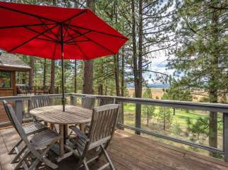Enjoy breathtaking views from this stunning deck, complete with a charming wooden dining set and a vibrant red umbrella, perfect for al fresco dining.
