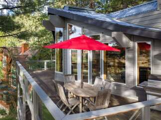 Enjoy outdoor living on this spacious deck, complete with a dining set and a vibrant red umbrella, perfect for al fresco meals.