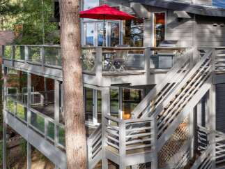 Experience outdoor living at its finest on this multi-level deck, complete with a vibrant red umbrella and a built-in grill, perfect for entertaining.