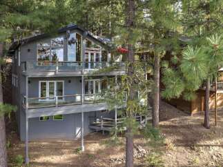 Nestled among tall pine trees, this multi-level modern home offers stunning natural views and ample outdoor living space.