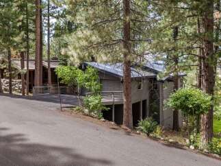 Nestled amongst towering pine trees, this modern home offers a serene retreat with its striking architecture and natural surroundings.