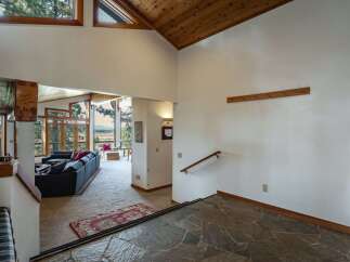 Experience breathtaking mountain views from this stunning home, featuring a spacious living area with a large sectional sofa and a cozy fireplace.