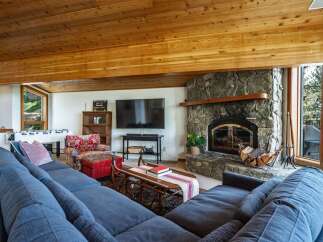 Experience cozy living in this spacious living room, featuring a grand stone fireplace perfect for chilly evenings.