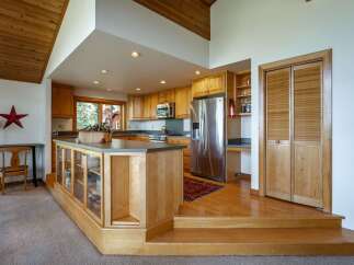 This spacious kitchen boasts beautiful natural wood cabinetry and a large island with glass display cabinets, perfect for showcasing your favorite items.