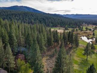 Nestled amidst a dense forest, this property offers a serene retreat with stunning views of a nearby golf course and tranquil water features.