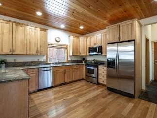 This spacious kitchen boasts beautiful natural wood cabinetry and a coordinating wood-paneled ceiling, creating a warm and inviting atmosphere.