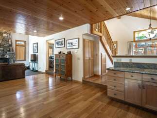 Experience rustic charm in this inviting living space featuring a grand stone fireplace and warm wood-paneled ceilings.