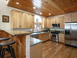 Experience rustic charm in this beautifully appointed kitchen, featuring warm wood cabinetry and a stunning granite-topped breakfast bar perfect for casual dining.