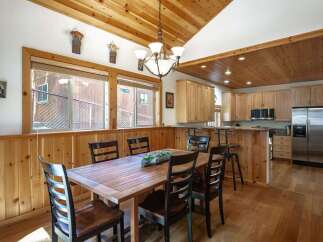 This charming dining area and kitchen boasts a warm, rustic aesthetic with extensive natural wood finishes throughout.