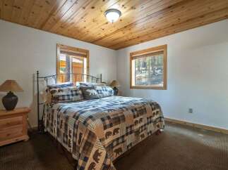 Experience rustic charm in this cozy bedroom featuring a comfortable queen-size bed adorned with a charming bear-themed quilt.