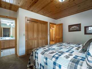 Experience rustic charm in this cozy bedroom featuring a comfortable bed adorned with a charming bear-themed quilt.