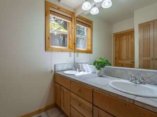 This charming bathroom features a double vanity with a tiled countertop and wooden cabinetry, offering ample storage.