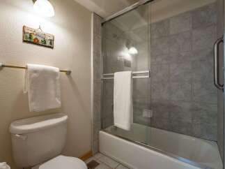 This bathroom features a clean white toilet and a bathtub with a glass shower enclosure.