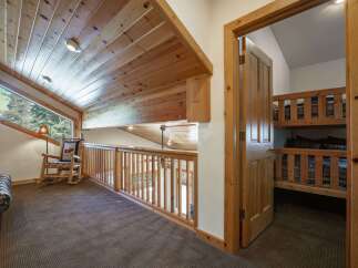 Discover this charming loft area featuring a cozy reading nook with a rocking chair and a unique angled window offering scenic views.