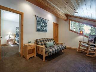 Experience rustic charm in this cozy bedroom featuring a comfortable futon and a rocking chair perfect for relaxing.