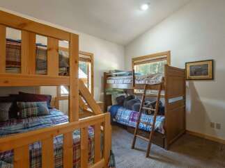 This charming bedroom features multiple wooden bunk beds, perfect for accommodating family and friends.