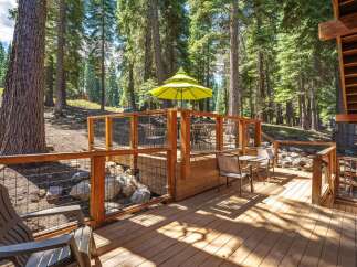 Enjoy the serene mountain lifestyle on this expansive wooden deck, perfect for outdoor entertaining amidst a lush forest setting.