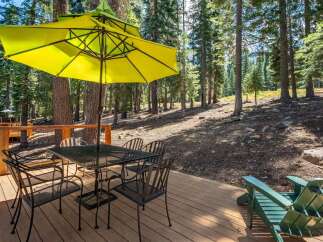 Enjoy outdoor dining and relaxation on this spacious wooden deck, nestled amongst tall pine trees.