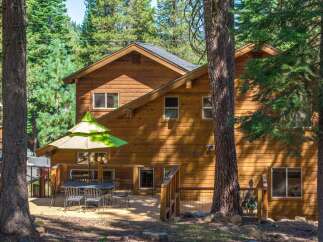 Enjoy outdoor living on this spacious wooden deck, perfect for entertaining or relaxing amidst the serene forest setting.