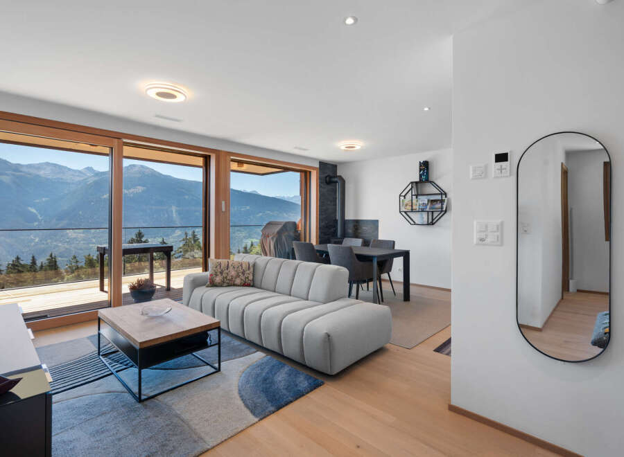 Experience breathtaking mountain views from this modern living space, featuring a plush sectional sofa and a stylish coffee table.