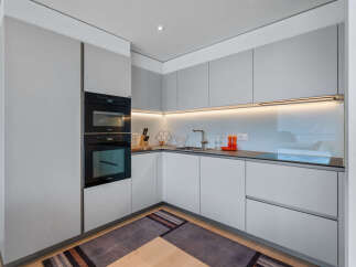 Experience modern living in this sleek, minimalist kitchen featuring integrated Miele appliances, including stacked ovens for ultimate culinary convenience.
