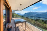 Experience breathtaking mountain vistas from this stunning modern balcony, featuring a sleek glass railing and a stylish outdoor table.