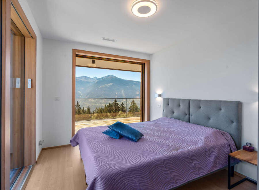 Experience breathtaking mountain views from this stunning bedroom, featuring a large sliding glass door that opens to a private balcony.