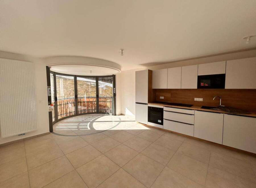 Discover modern living in this spacious apartment featuring a sleek, integrated kitchen with ample cabinet space and a built-in oven and microwave.