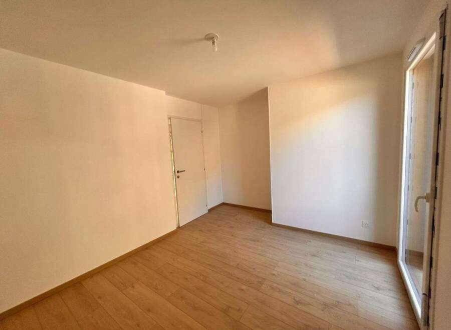 Experience modern living in this bright and airy room, featuring a pristine white door and a large glass door leading to an outdoor space.