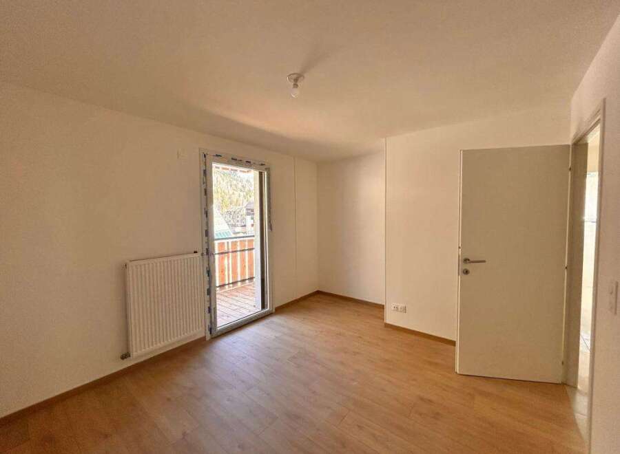 Discover this bright and airy room featuring a modern radiator and a large glass door leading to a balcony with scenic views.